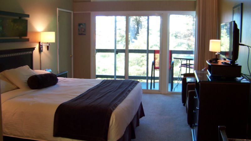 Inn room with king bed, dresser, media center.